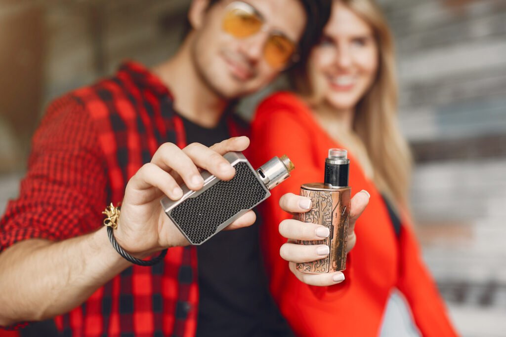 stylish young couple with vape in a city
