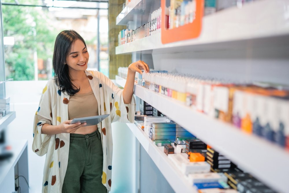 female,seller,checking,the,liquid,stock,at,the,shelf,using
