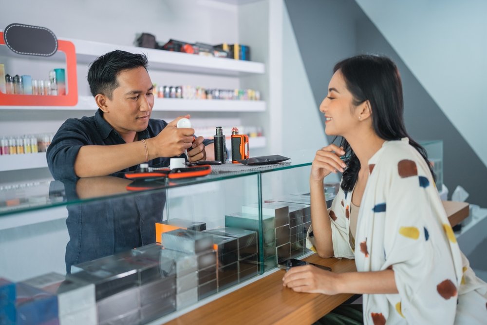 male,vape,seller,helping,the,female,customer,to,refill,the